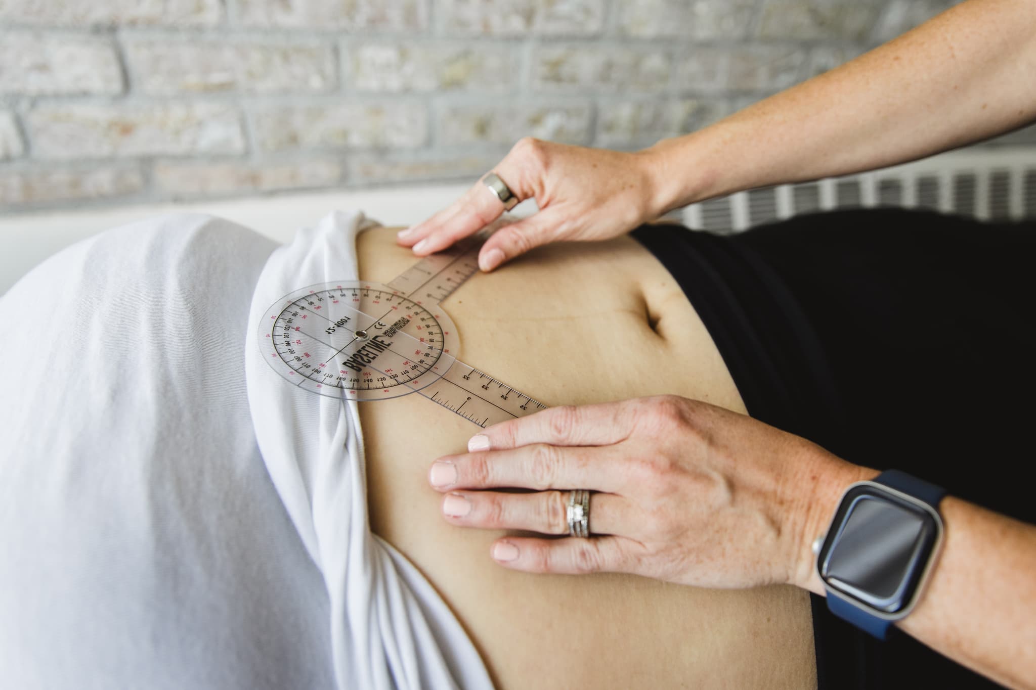 Detail image demonstrating patient laying on therapy table while pelvic floor physical therapist gets an accurate reading of the postpartum patients ribcage angle.
