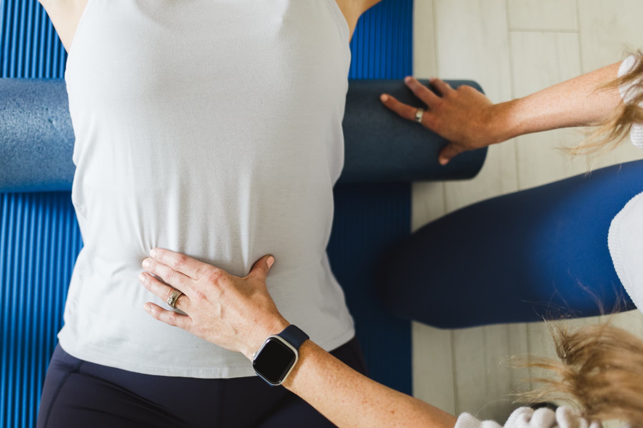 Close up superior view of a patient laying over a foam roller while therapist assesses abdominal activation.