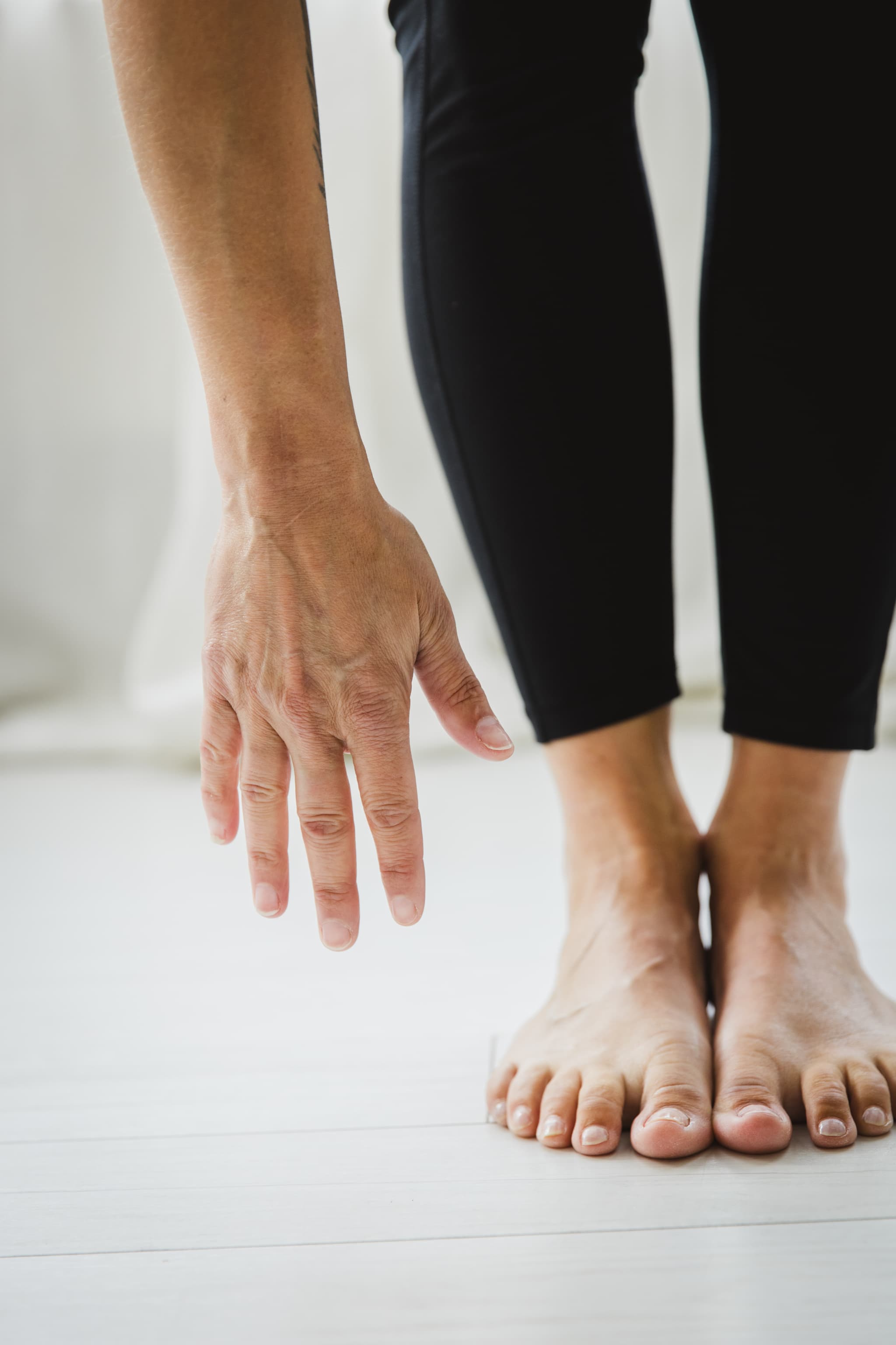 Close up image of a woman bending forward reaching for her toes to stretch out her back and legs.